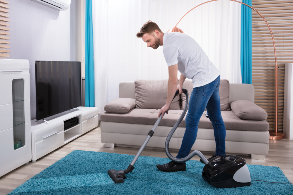 10 Tips for Effective Vacuum Cleaning: A Guide from Neatstore Person vacuuming carpet in Lagos Nigerian home using affordable vacuum cleaner